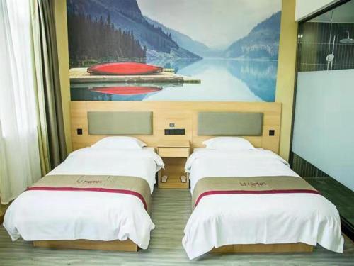two beds in a room with a painting on the wall at Thank Inn Chain Hotel Hebei Handan Wu'an City Bus Station in Handan