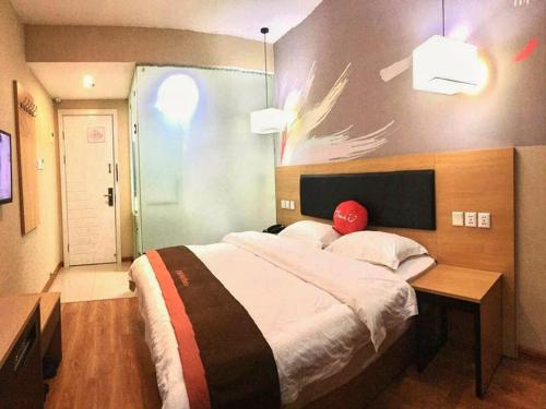 a bedroom with a large bed with a red hat on it at JUN Hotels ujian Fuzhou Jinan District Railway Station in Fuzhou