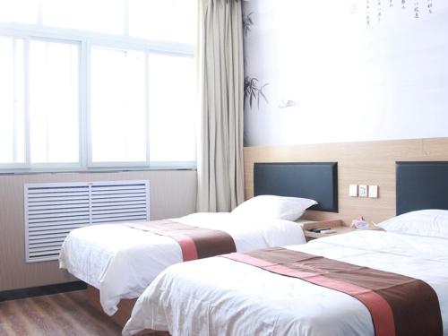 a hotel room with two beds and a window at JUN Hotels Hebei Langfang Guangyang Langfang Station in Langfang