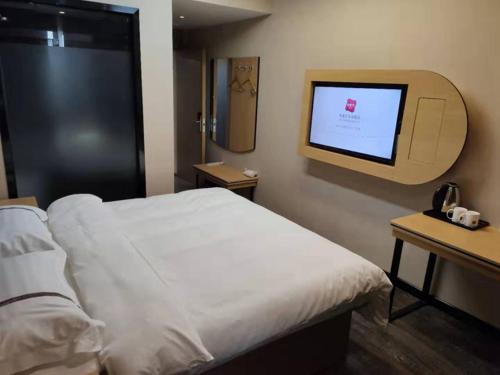 a hotel room with a bed and a flat screen tv at Thank Inn Chain Hotel Luoyang Mengjin County Yellow River Avenue Bus Station in Luoyang