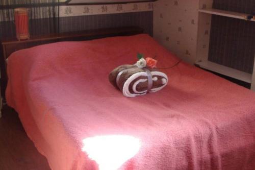un animal farci sur un lit avec une couverture rose dans l'établissement breil sur roya, à Breil-sur-Roya