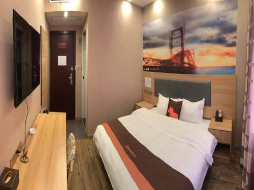 1 dormitorio con 1 cama grande y una pintura en la pared en JUN Hotels Hunan Zhuzhou Shifeng District Qingshi Plaza en Zhuzhou