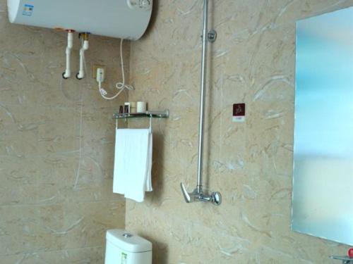 a bathroom with a toilet and a towel dispenser at JUN Hotels Shanxi Lvliang Lishi District Lvliang Academy West Gate in Luliang