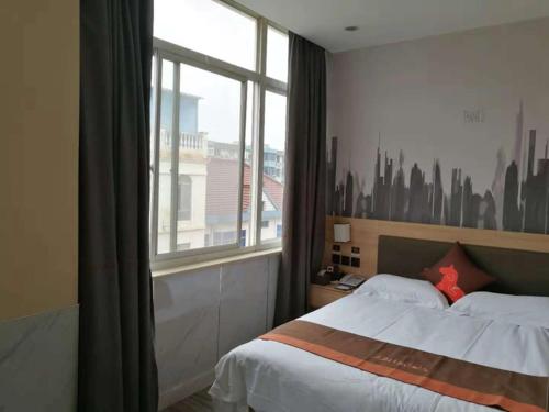 a bedroom with a bed with a view of a city at JUN Hotels Zhejiang Jiaxing Haiyan Qiyuan North Road in Jiaxing