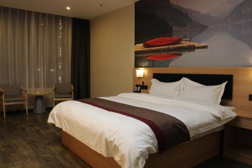 KaibaにあるThank Inn Chain Hotel Qinghai Haixi Wulan Xinghai Business Streetの大きなベッドとテーブルが備わるホテルルームです。