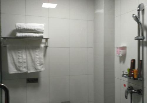 a bathroom with a shower with white towels at JUN Hotels Anyang Beiguan District Railway Station in Anyang