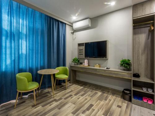 a room with a table and chairs and a television at JUN Hotels Shanxi Taiyuan Yingze District Chaoyang Street Store in Taiyuan