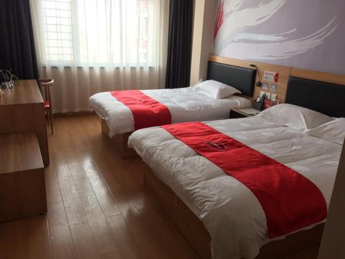石家荘市にあるThank Inn Chain Hotel Hebei Shijiazhuang Jinzhou New Times Auto Plazaのベッド2台(赤と白のシーツ付)が備わる客室です。