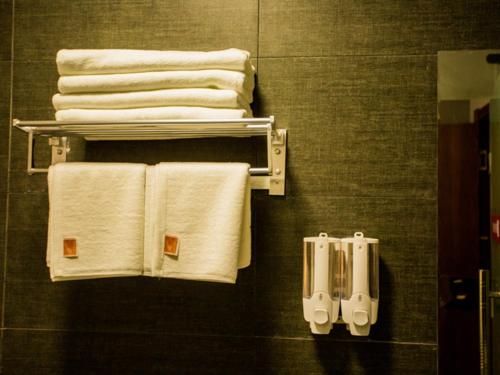 un grupo de toallas colgadas en la pared del baño en JUN Hotels Shandong Heze Mudan District Sanjiao Garen, en Heze