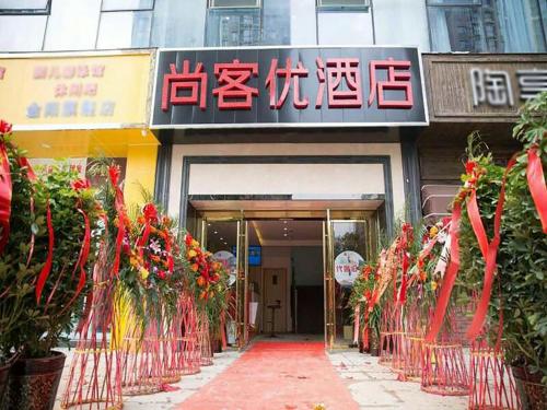 una entrada a un edificio con señales rojas y flores en Thank Inn Chain Hotel Guizhou Guiyang Guanshanhu District Century City Store, en Guiyang