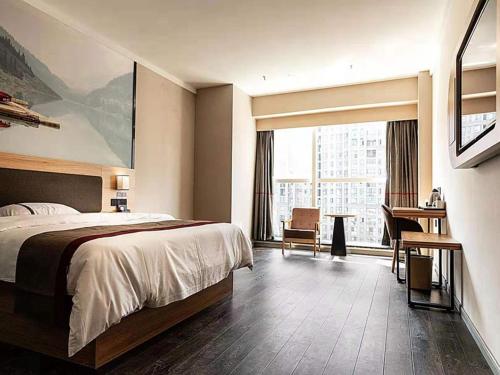 a hotel room with a bed and a desk and a window at Thank Inn Chain Hotel Hefei Baohe District Highspeed Times Square in Hefei