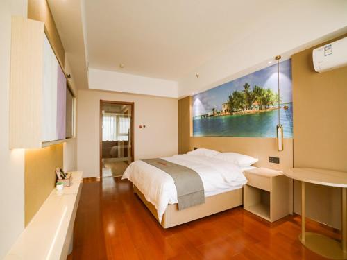 a bedroom with a large bed with a painting on the wall at JUN Hotels Liaoning Anshan Railway Station Wanxianghui in Anshan