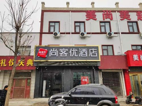 a black car parked in front of a building at Thank Inn Chain Hotel Luoyang Mengjin County Yellow River Avenue Bus Station in Luoyang