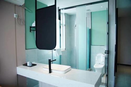 een badkamer met een wastafel, een spiegel en een toilet bij JUN Hotels Shanxi Taiyuan Gaoxin Community in Taiyuan