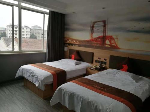 a hotel room with two beds and a large window at JUN Hotels Zhejiang Jiaxing Haiyan Qiyuan North Road in Jiaxing