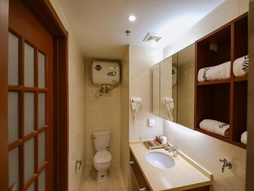 a bathroom with a toilet and a sink and a mirror at JUN Hotels Liaoning Anshan Railway Station Wanxianghui in Anshan