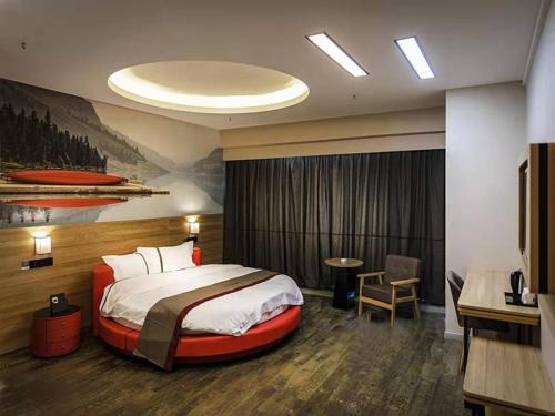 een hotelkamer met een groot bed en een bureau bij Thank Inn Chain Hotel Hefei Baohe District Highspeed Times Square in Hefei
