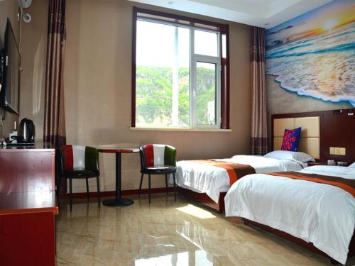 a hotel room with two beds and a table and a window at JUN Hotels Shanxi Lvliang Lishi District Lvliang Academy West Gate in Luliang