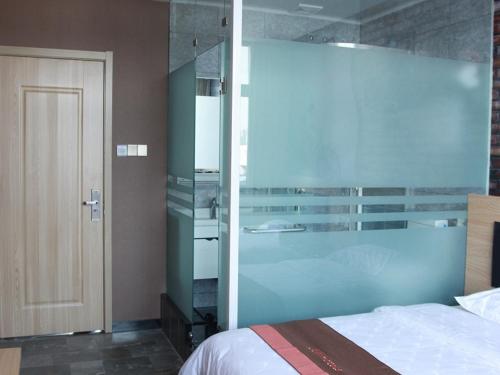 a bedroom with a bed and a glass wall at JUN Hotels Hebei Langfang Guangyang Langfang Station in Langfang