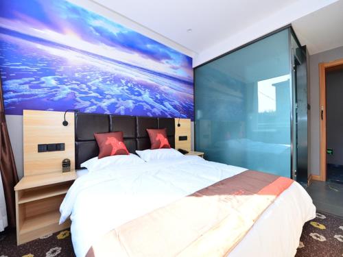 a bedroom with a large bed with a painting on the wall at JUN Hotels Shanxi Changzhi Xiangyuan Taihang Road JuranZhijia in Changzhi