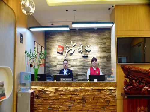 dos hombres sentados en un mostrador en una oficina en Thank Inn Chain Hotel Heilongjiang Jiamusi Qianjin District Railway Station, en Jiamusi