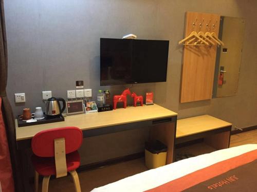 a desk in a hotel room with a red chair at JUN Hotels Dezhou Decheng District Xinhu Park Pedestrian Street in Dezhou