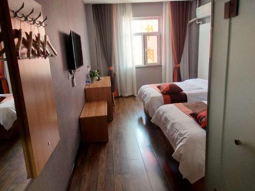 a hotel room with two beds and a television at JUN Hotels Hebei Hengshui Taocheng District Heping West Road in Hengshui