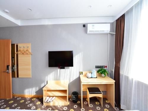 a room with a desk and a tv on a wall at JUN Hotels Shanxi Changzhi Xiangyuan Taihang Road JuranZhijia in Changzhi