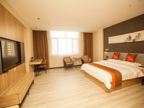 a bedroom with a bed and a desk and a television at JUN Hotels Hebei Shijiazhuang Wuji County Zhengyi Street Store in Shijiazhuang