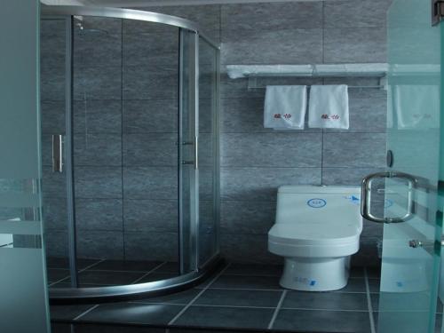a bathroom with a toilet and a shower with towels at JUN Hotels Hebei Langfang Guangyang Langfang Station in Langfang