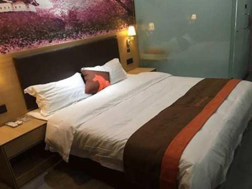 1 dormitorio con 1 cama grande con sábanas y almohadas blancas en JUN Hotels Xingtai Pingxiang County Jianshe Street, en Xingtai