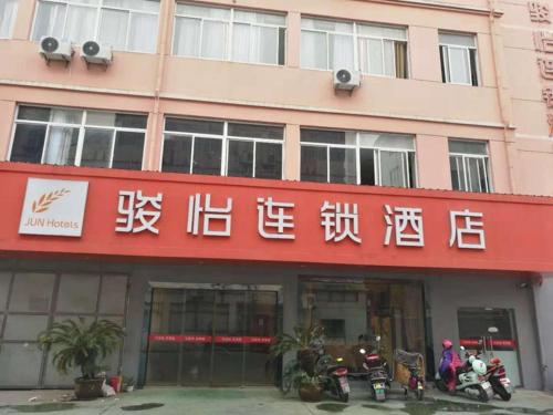 a red building with writing on it with motorcycles parked outside at JUN Hotels Zhejiang Jiaxing Haiyan Qiyuan North Road in Jiaxing