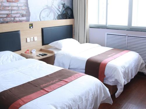 a hotel room with two beds and a television at JUN Hotels Hebei Langfang Guangyang Langfang Station in Langfang