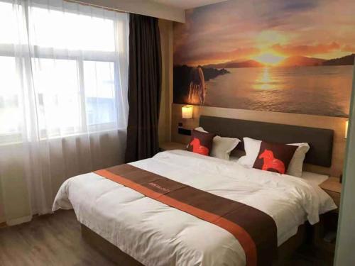 a bedroom with a large bed with a painting on the wall at JUN Hotels Shandong Liaocheng Dong'a County Bus Station Store in Liaocheng