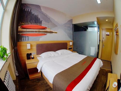a bedroom with a large bed and a painting on the wall at Thank Inn Chain Hotel Heilongjiang Jiamusi Qianjin District Railway Station in Jiamusi