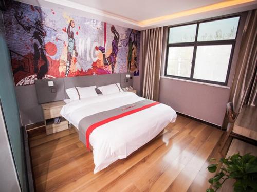 a bedroom with a large bed and a painting on the wall at JUN Hotels Shandong Heze Development Zone Shanghai Road in Xinji