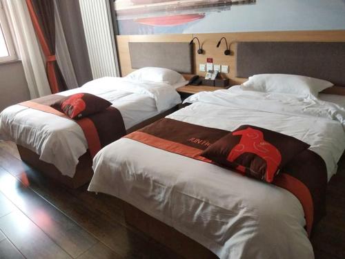 two beds in a hotel room next to each other at JUN Hotels Hebei Hengshui Taocheng District Heping West Road in Hengshui