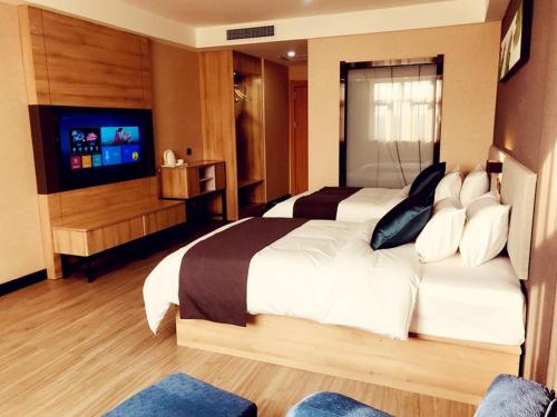 a bedroom with a large bed and a flat screen tv at Up And In Kashgar Shache County Buxing Street in Shache