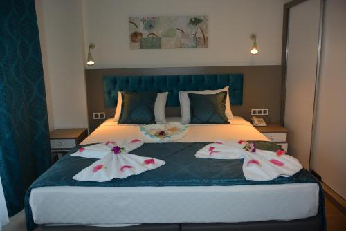 a bedroom with a bed with two dresses on it at THE NORDİC HOTEL in Kemer