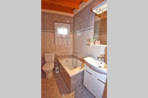 a bathroom with a tub and a toilet and a sink at Traditional House with Amazing View in Chlomós