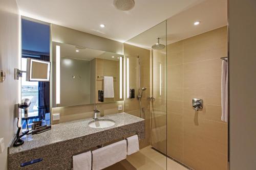 a bathroom with a sink and a shower at Steigenberger Airport Hotel Berlin in Schönefeld