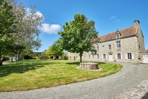 an old stone building with a tree in front of it at Manoir de l’Ormel Omaha Beach in Vierville-sur-Mer