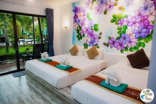 two beds in a room with flowers on the wall at Siri Lanta Resort in Ko Lanta