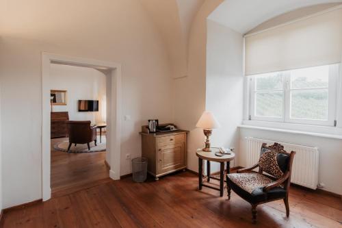 a living room with a chair and a table and a window at Freigut Thallern in Gumpoldskirchen