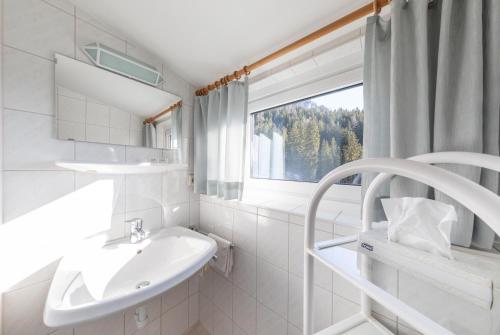 a white bathroom with a sink and a window at Alpenhof in Ramsau am Dachstein