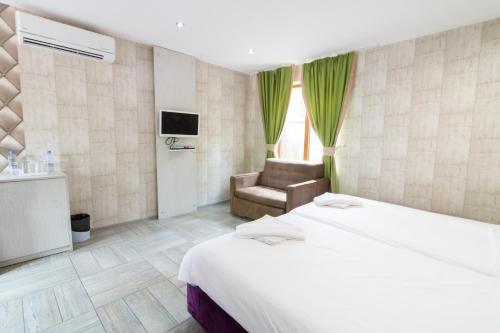a hotel room with a bed and a chair at Elinor Complex in Haskovo