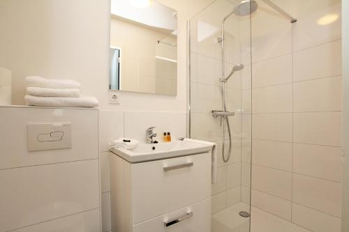 a white bathroom with a sink and a shower at Citystays Deventer in Deventer