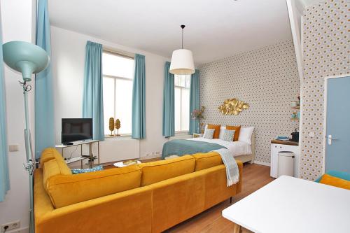 a living room with a yellow couch and a bedroom at Citystays Deventer in Deventer