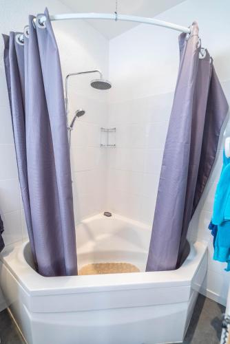 a bathtub with purple shower curtains in a bathroom at La Maïoun Guesthouse in Nice