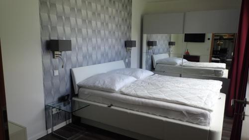 2 camas blancas en una habitación con espejo en Strandmuschel en Ostseebad Sellin